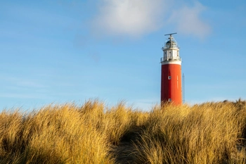 Red and white lighthouse under blue sky during daytime