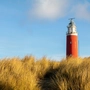 Red and white lighthouse under blue sky during daytime